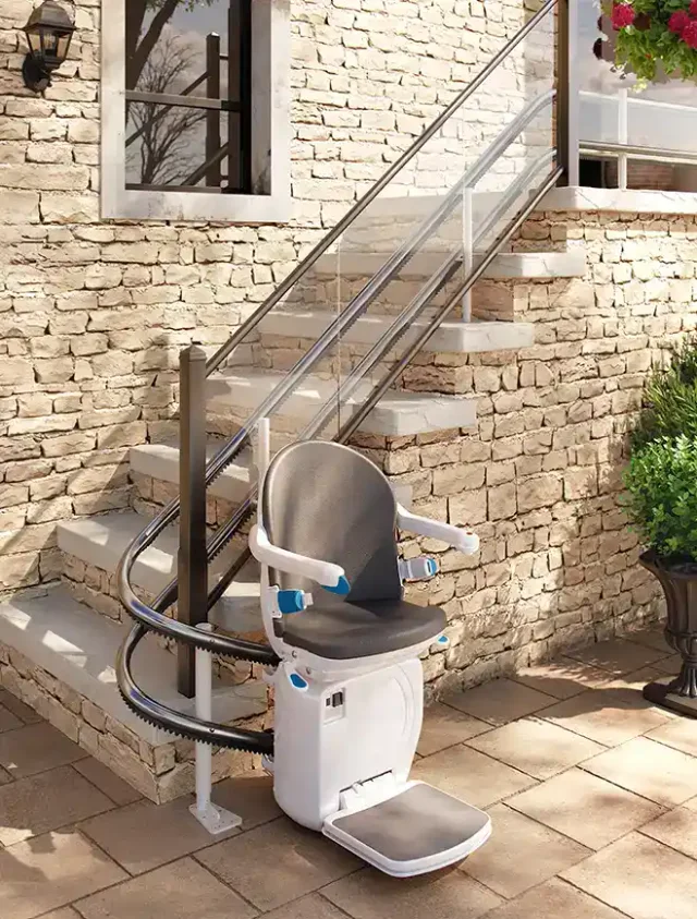 A twin-rail curved stairlift on outdoor stone steps