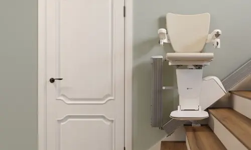 A stairlift folded flat beside a white interior door