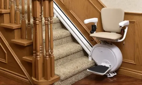 A stairlift with a beige seat matched to a golden oak staircase
